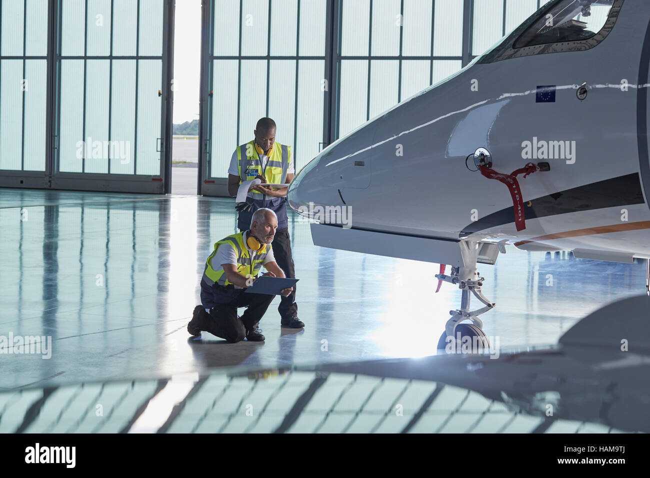 Il controllo del traffico aereo il personale a terra i lavoratori valutando corporate jet in hangar aereo Foto Stock