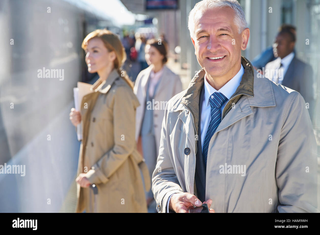 Ritratto di imprenditore sorridente sulla soleggiata stazione ferroviaria platform Foto Stock