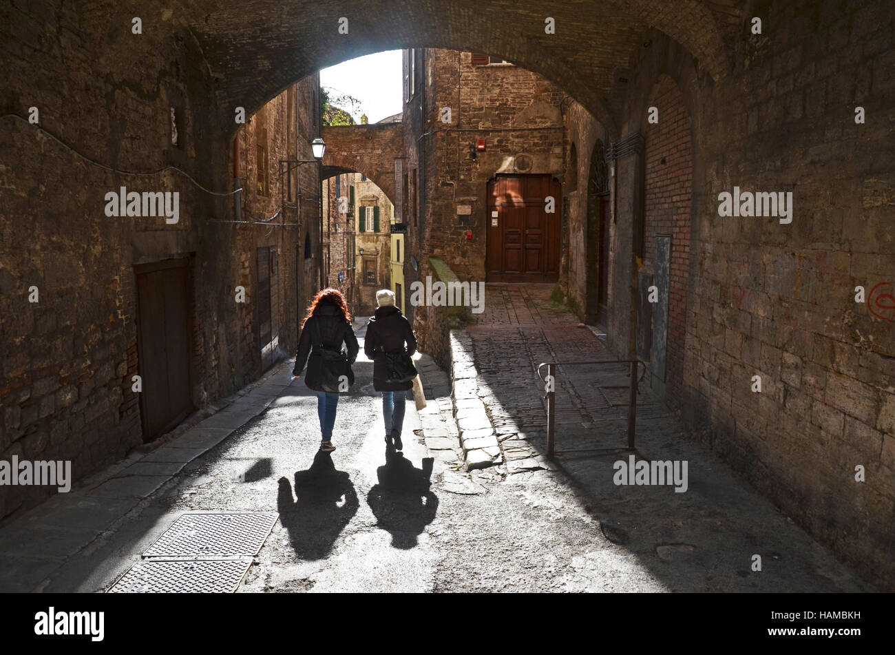 Due donne a piedi attraverso un arco a Perugia, Umbria, Italia Foto Stock