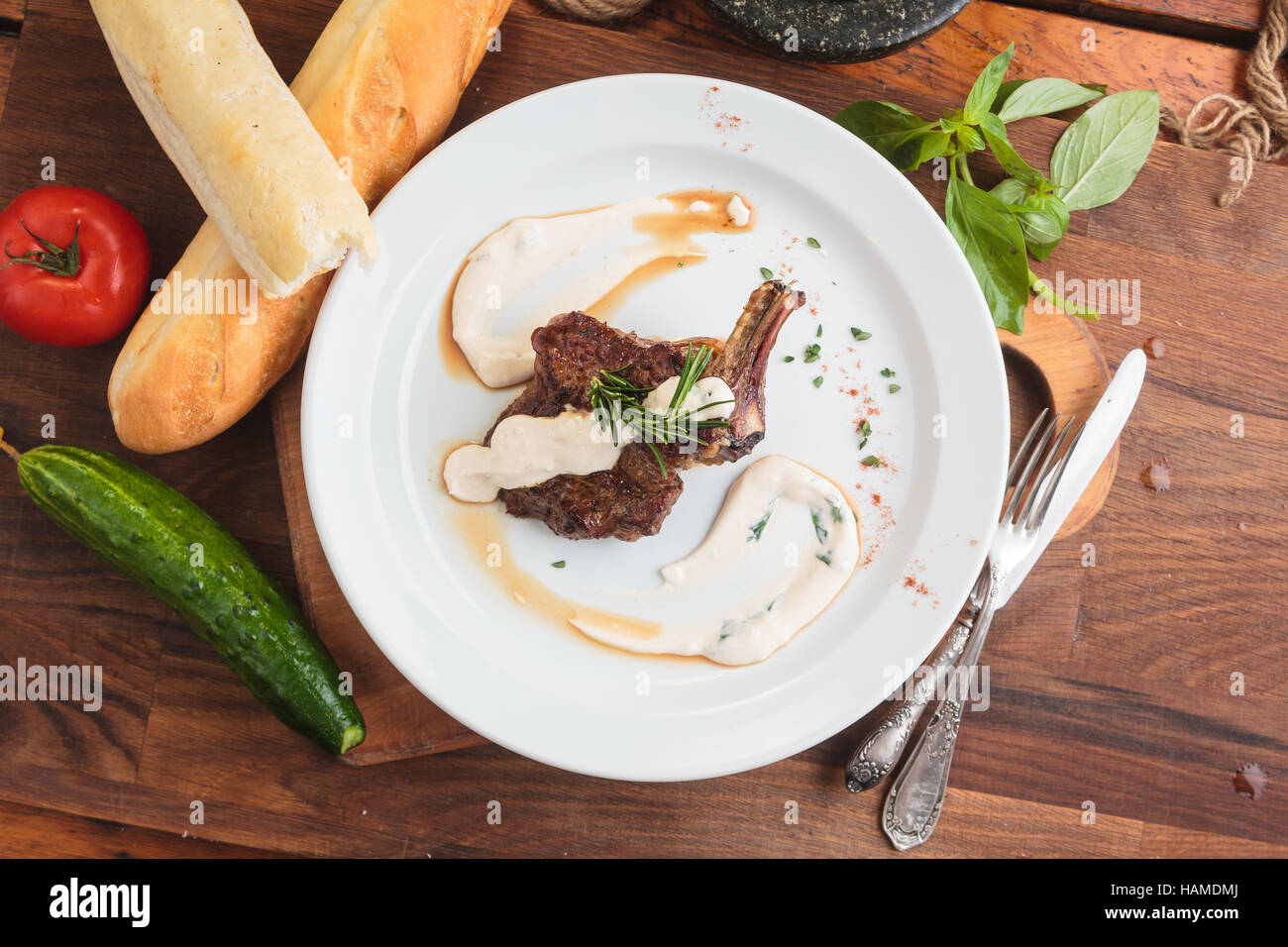 Concetto: ristorante menu, mangiare sano, fatti in casa, golosi, golosità. Piastra bianca di agnello cremagliera sul tavolo di legno e gli ingredienti su sfondo. Top- Foto Stock