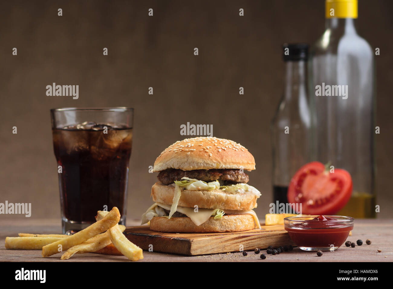 Concetto: ristorante menu, mangiare sano, fatti in casa, golosi, golosità. Carni bovine Classic double burger con gli ingredienti, bevande e patatine fritte sul disordine Foto Stock