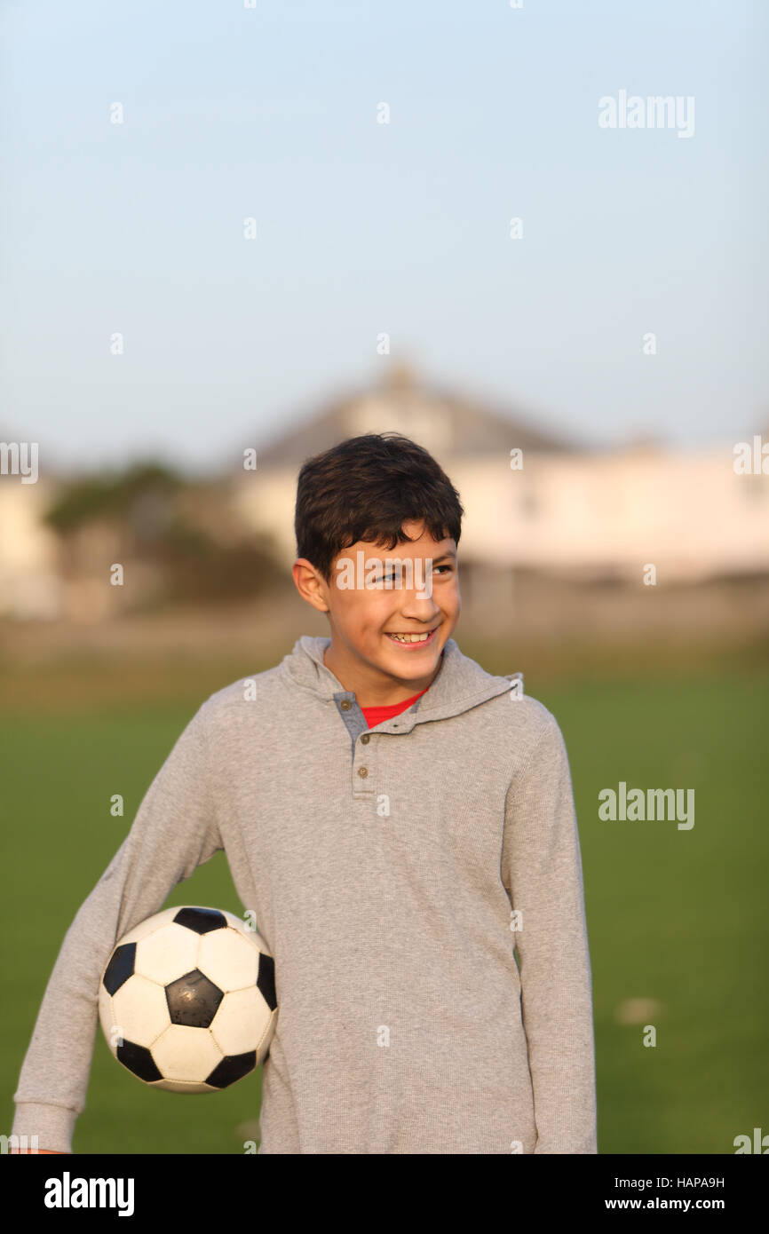 Ragazzo con pallone da calcio al di fuori del golden ora vicino al tramonto Foto Stock