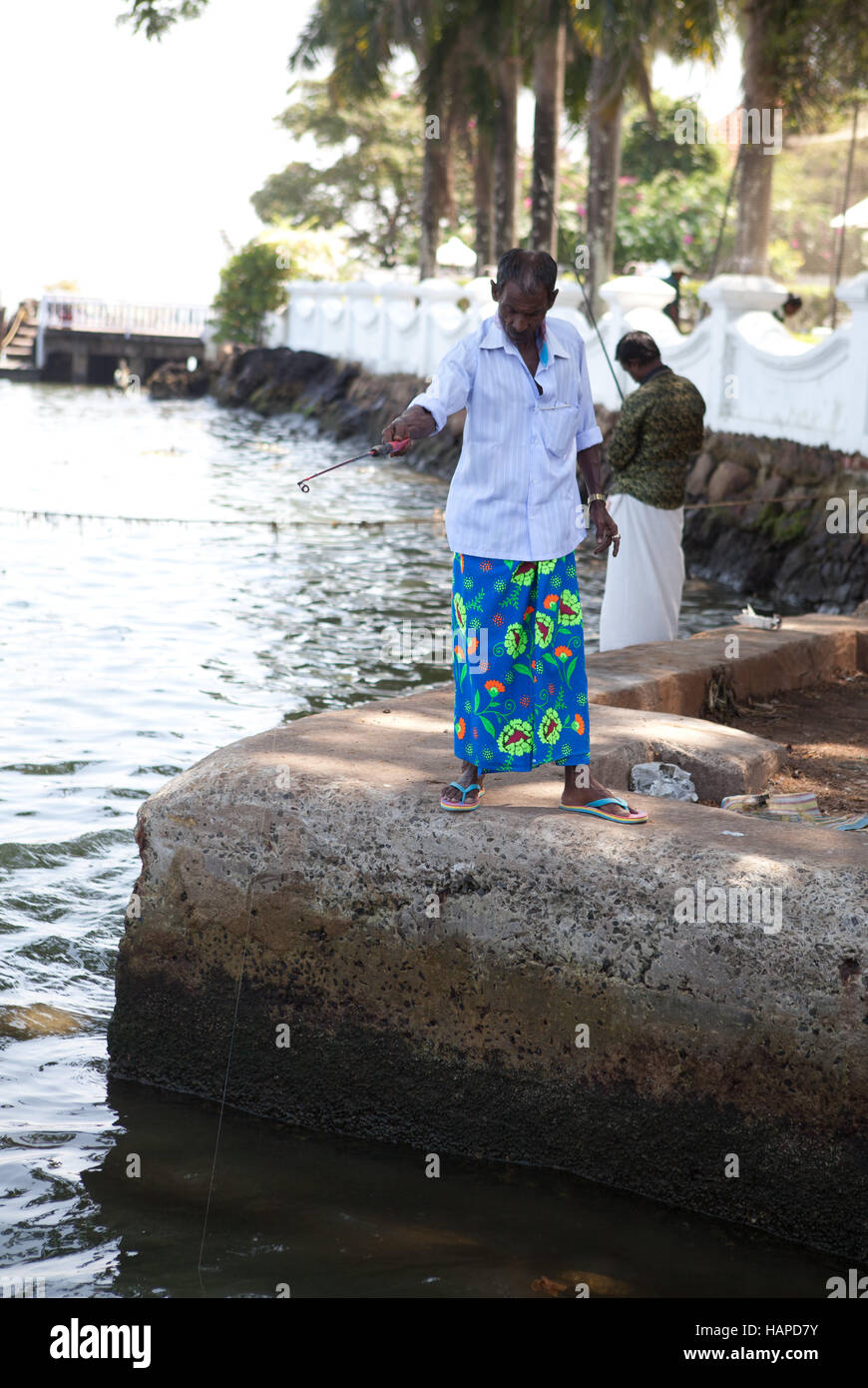 Gli uomini la pesca vicino al traghetto il terminale,Fort Cochin,Kochi, Kerala, India. Foto Stock