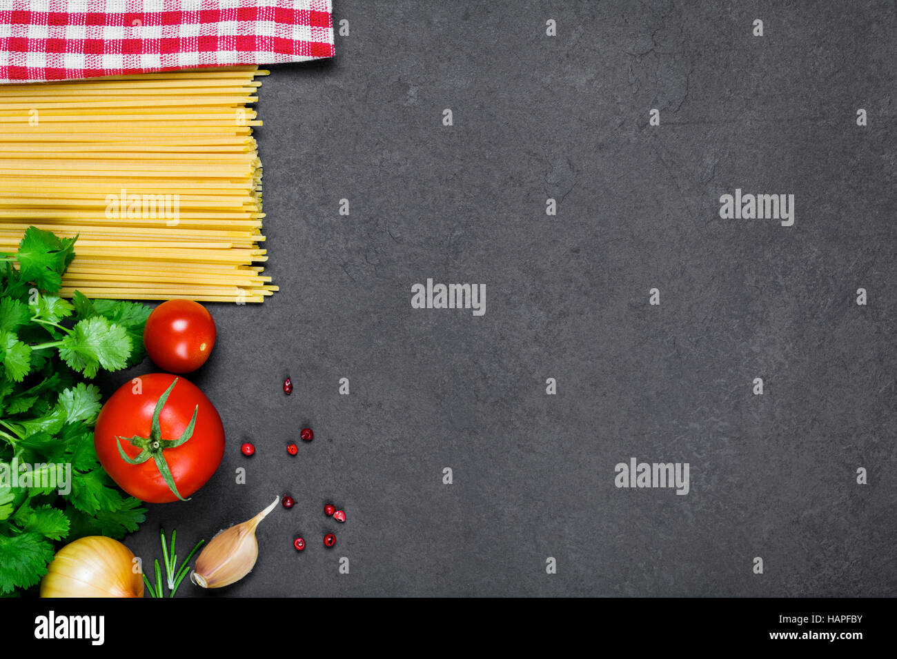 Cottura ingredienti per la cucina italiana: pasta spaghetti, i pomodori, il prezzemolo, la cipolla, l'aglio, pepe rosso e plaid igienico Foto Stock