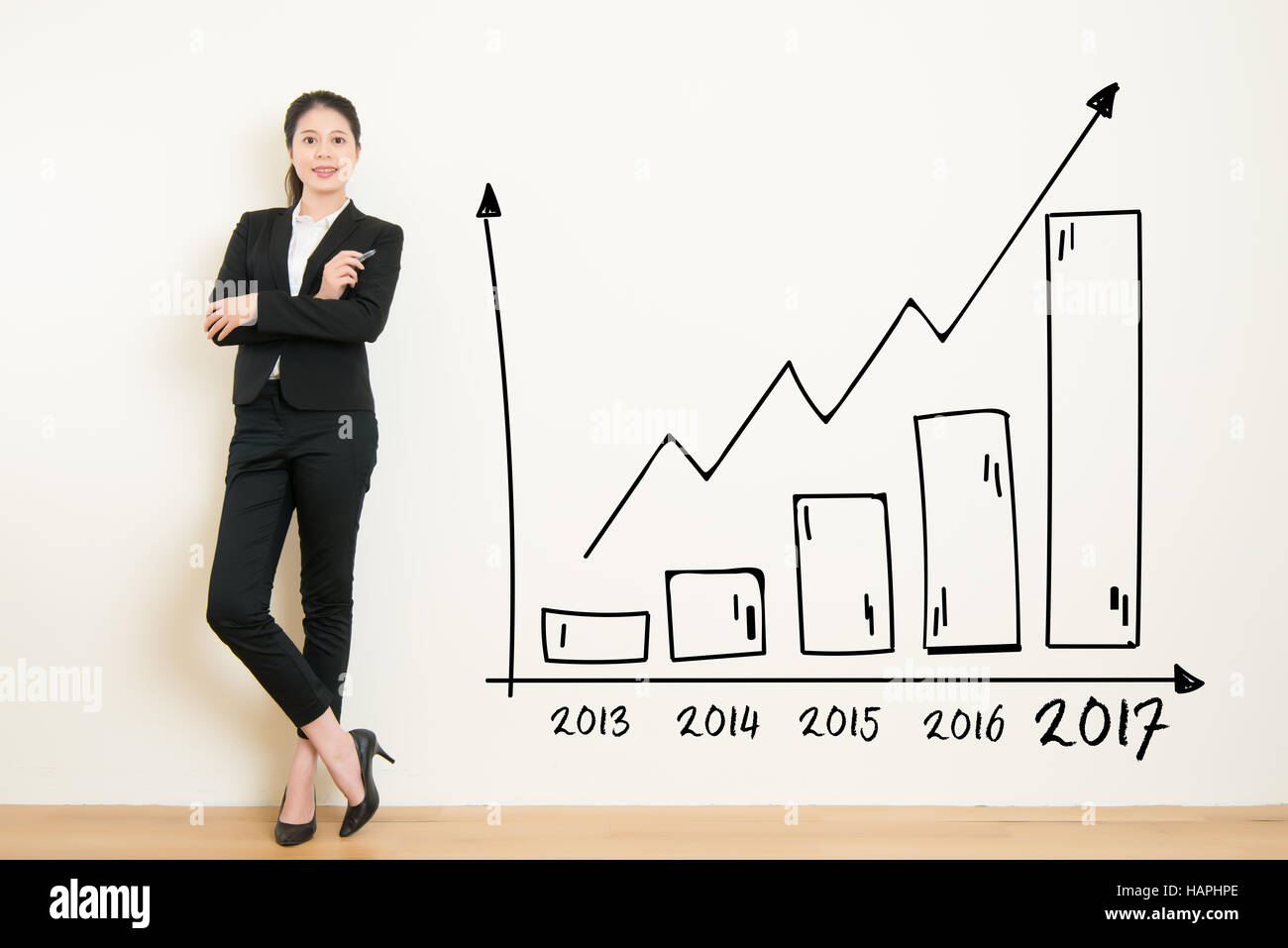 Business donna disegno grafico che mostra la crescita di profitto sul muro bianco sullo sfondo. Asian imprenditrice isolati su sfondo bianco in tuta. bella miscelati Foto Stock