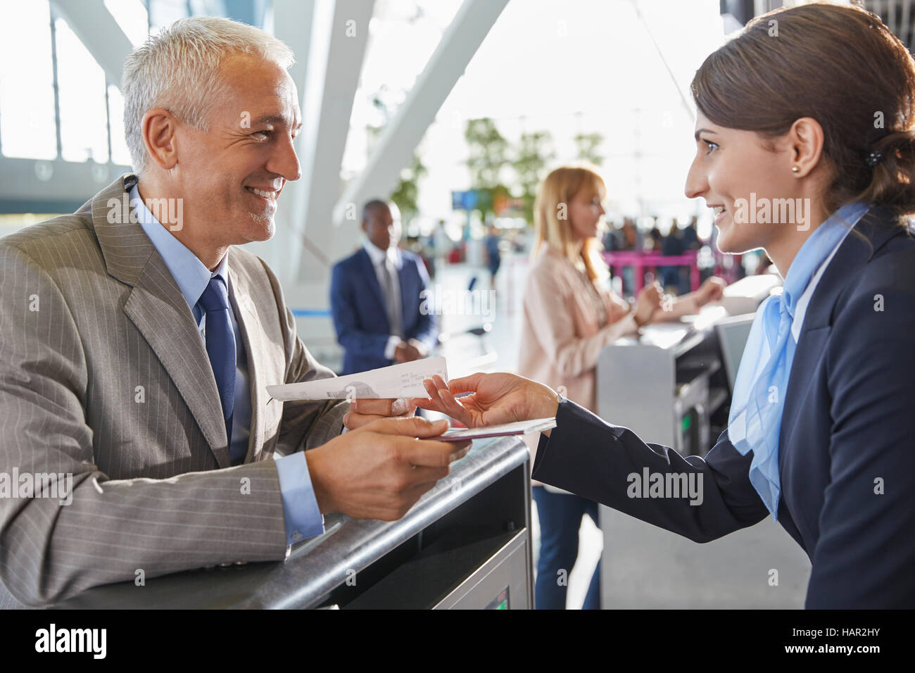 Rappresentante del servizio clienti aiutando imprenditore in aeroporto al banco check-in Foto Stock