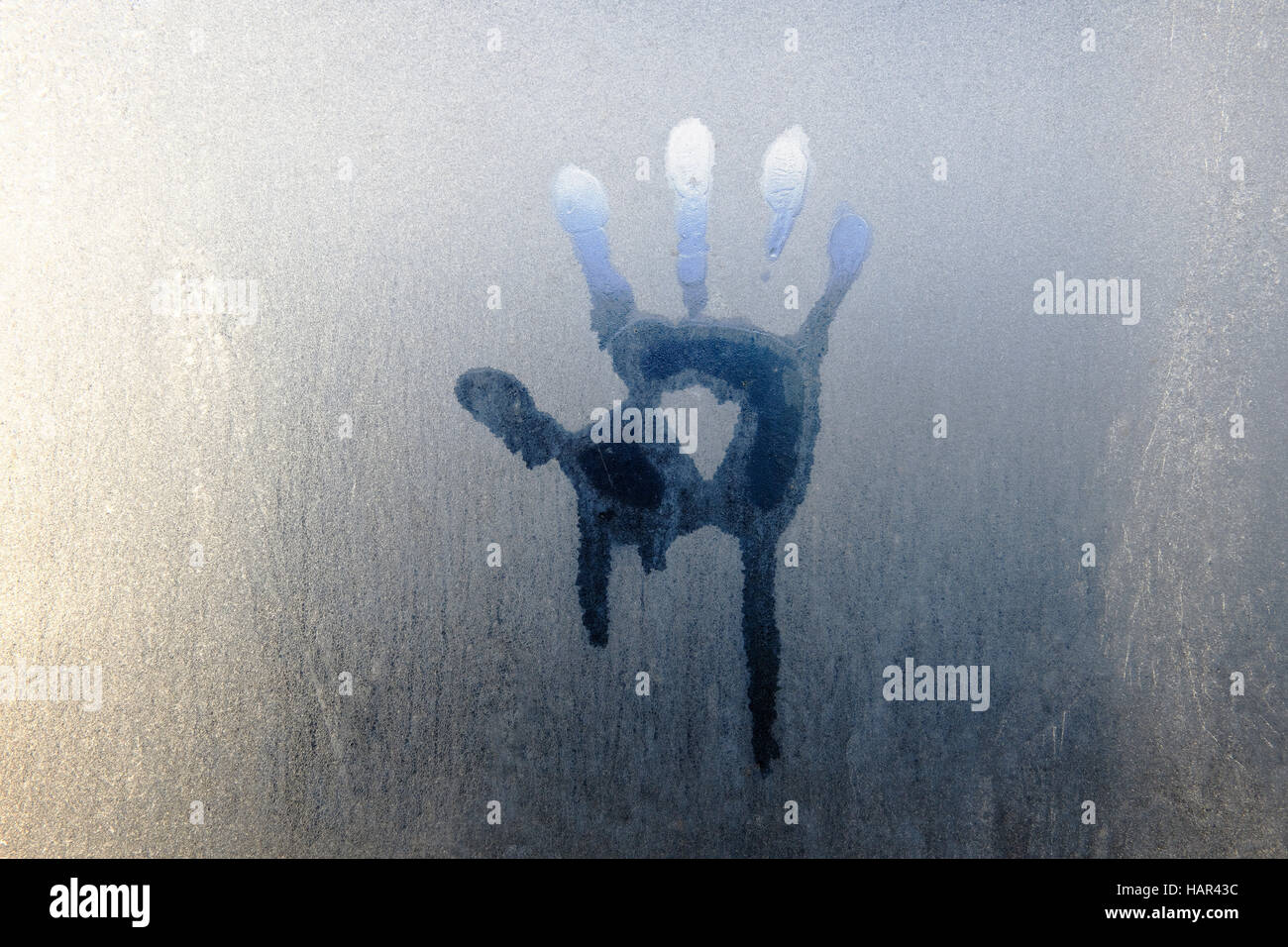 Impressione di mano fuso in trasformata per forte gradiente brina sulla finestra di serra. Retroilluminati da mattina presto sunshine Foto Stock