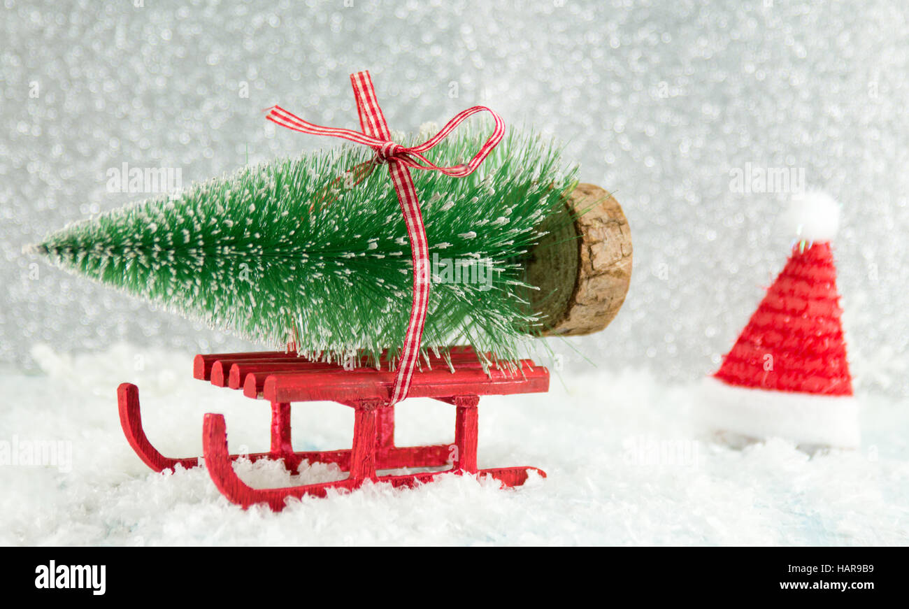 Inverno rosso slitta portante un piccolo albero di Natale Foto Stock