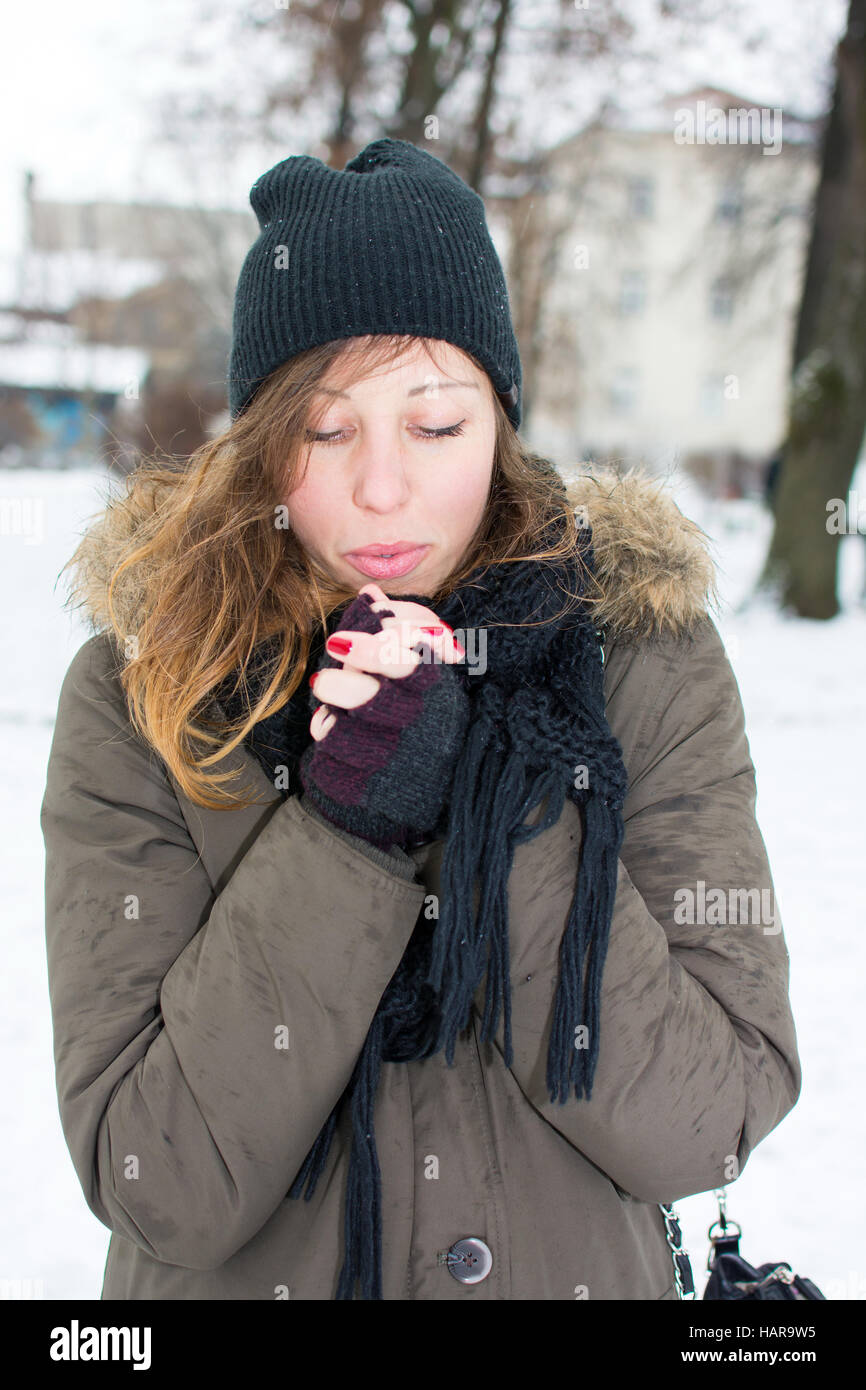 Donna riscaldare le mani in coperta di neve park Foto Stock