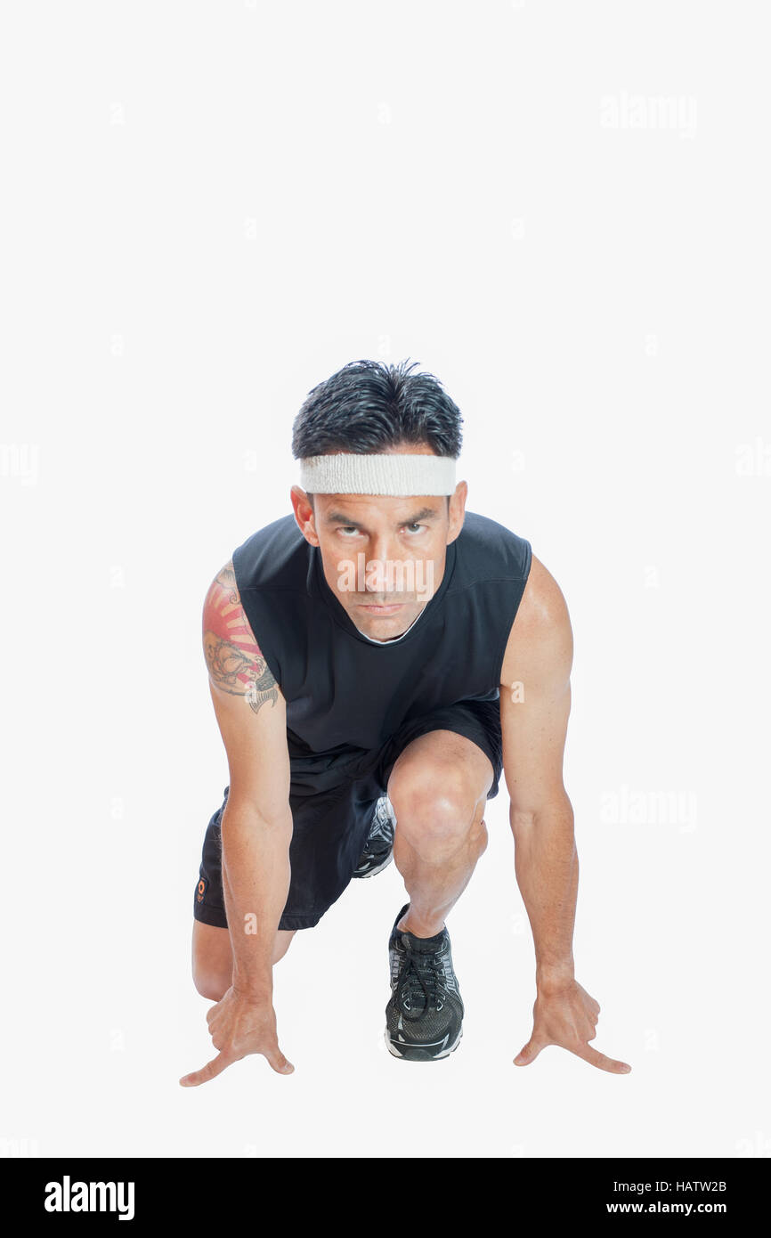 Oliva maschio scuoiate runner rannicchiato nella pronta per la posizione di sprint. Foto Stock