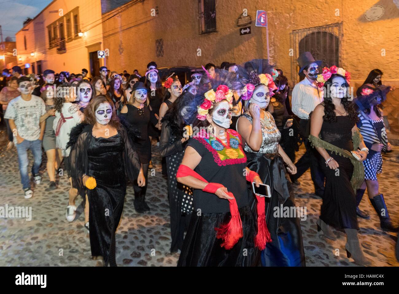 Gli studenti vestiti come la Calavera Catrina per il Giorno dei Morti festival parade attraverso il quartiere storico di San Miguel De Allende, Guanajuato, Messico. La settimana di festa è un momento in cui i messicani benvenuti i morti alla messa a terra per una visita e celebrare la vita. Foto Stock