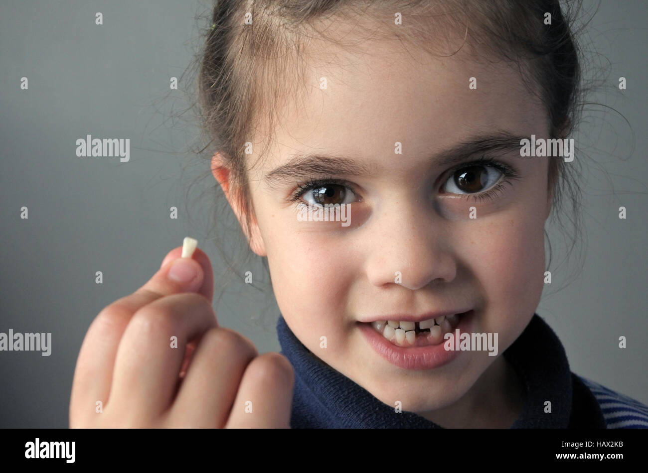 Orgogliosa ragazza giovane età (6) mantiene la sua prima caduta di denti di latte, guarda la telecamera. Infanzia Il concetto di assistenza sanitaria.la gente reale spazio di copia Foto Stock