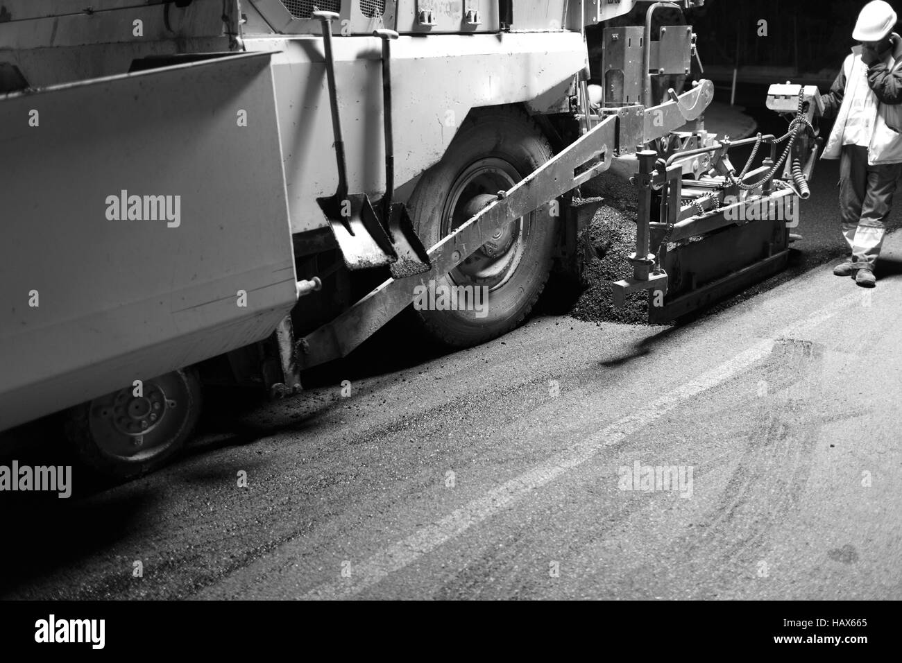 Macchina di pavimentazione di asfalto che si estende durante il turno di notte Foto Stock