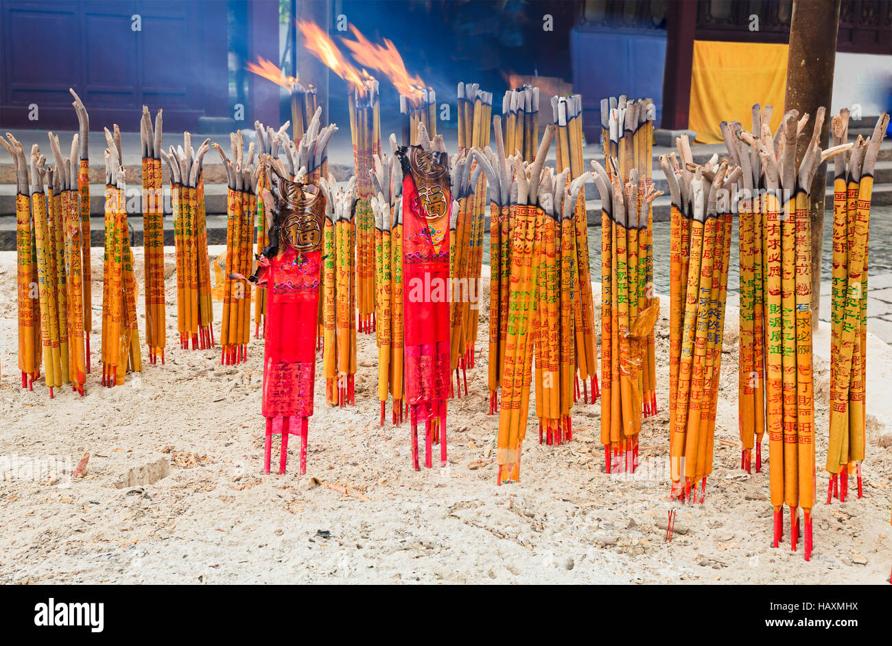 La masterizzazione di grappoli di orientare i bastoni in piedi nella sabbia trasformando in fiamme e cenere in cinese antico tempio. Foto Stock
