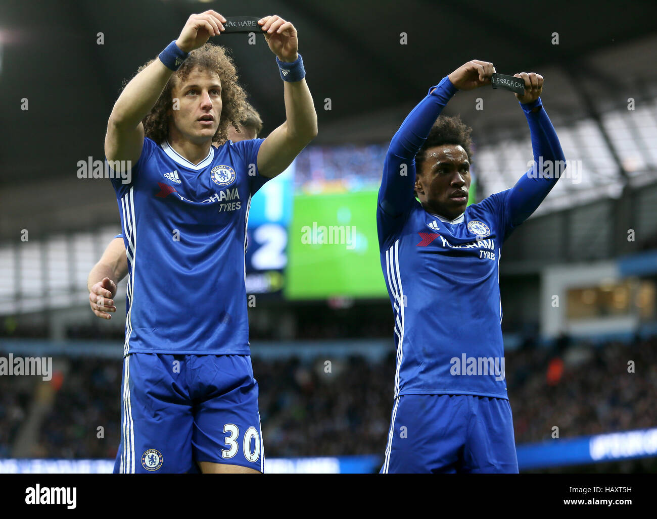 Chelsea David Luiz (sinistra) e Willian (destra) visualizzare le loro bande di braccio alla folla in ricordo del brasile calcio Chapecoense team che sono stati coinvolti nel piano Colombia crashduring la Premier League al Etihad Stadium e Manchester. Foto Stock