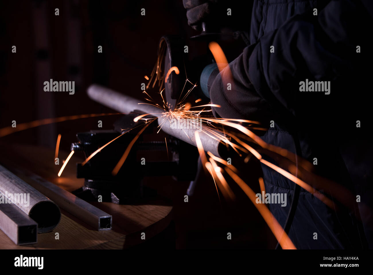 Lavoratore macinazione di tubazione di metallo con una macchina in officina Foto Stock