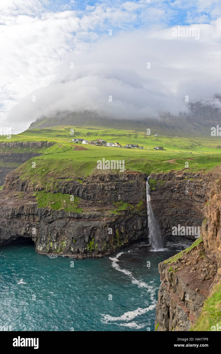 L'iconico cascata di Gasadalur su isole Faerøer e il remoto villaggio in background Foto Stock