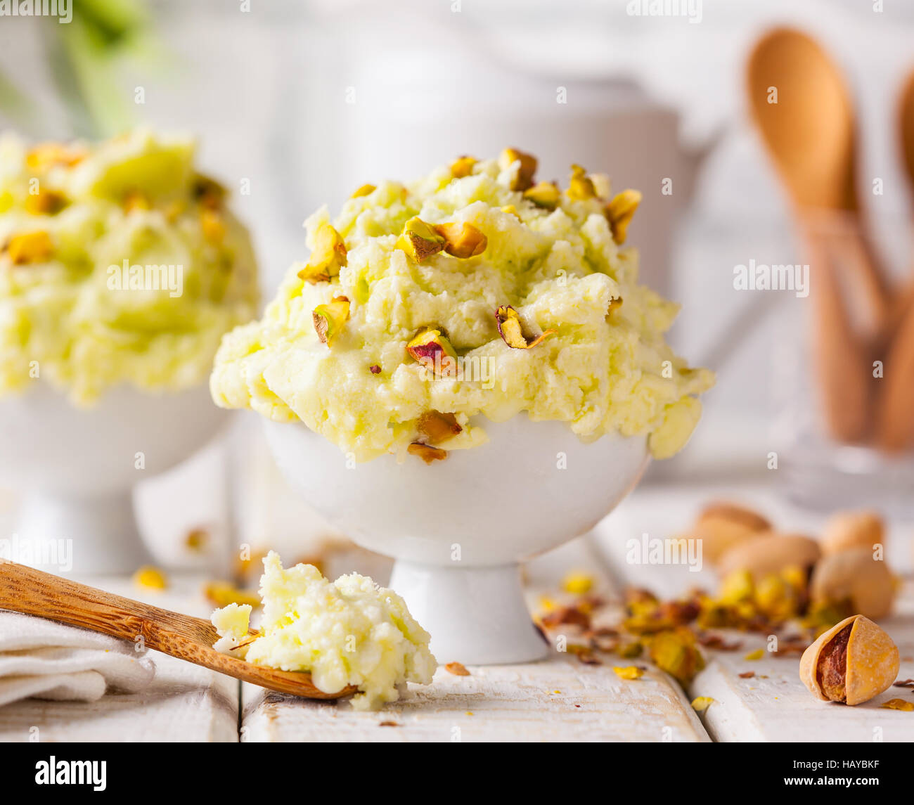 Una ciotola di pistacchio gelato con noci tritate e cucchiaio su un sfondo rustico. Foto Stock