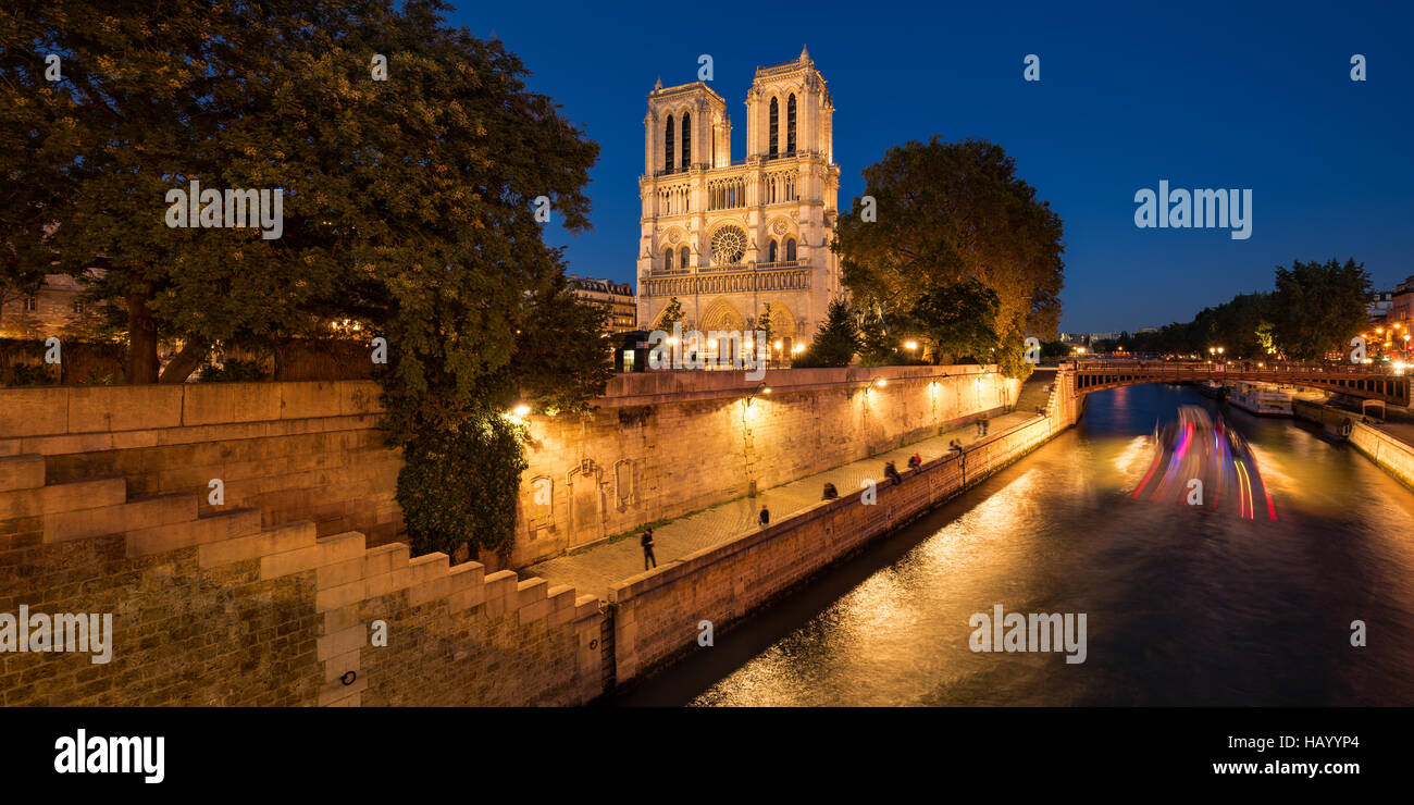 Notre Dame de Paris cathedral accesa al crepuscolo con il Fiume Senna e il Pont au Double. Ile de la Cite, Parigi, Francia Foto Stock