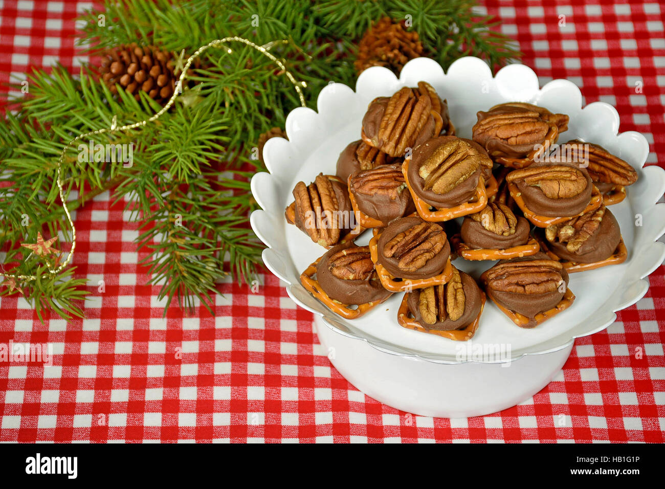 Le noci pecan sul cioccolato fuso e salatini con pino di Natale Foto Stock