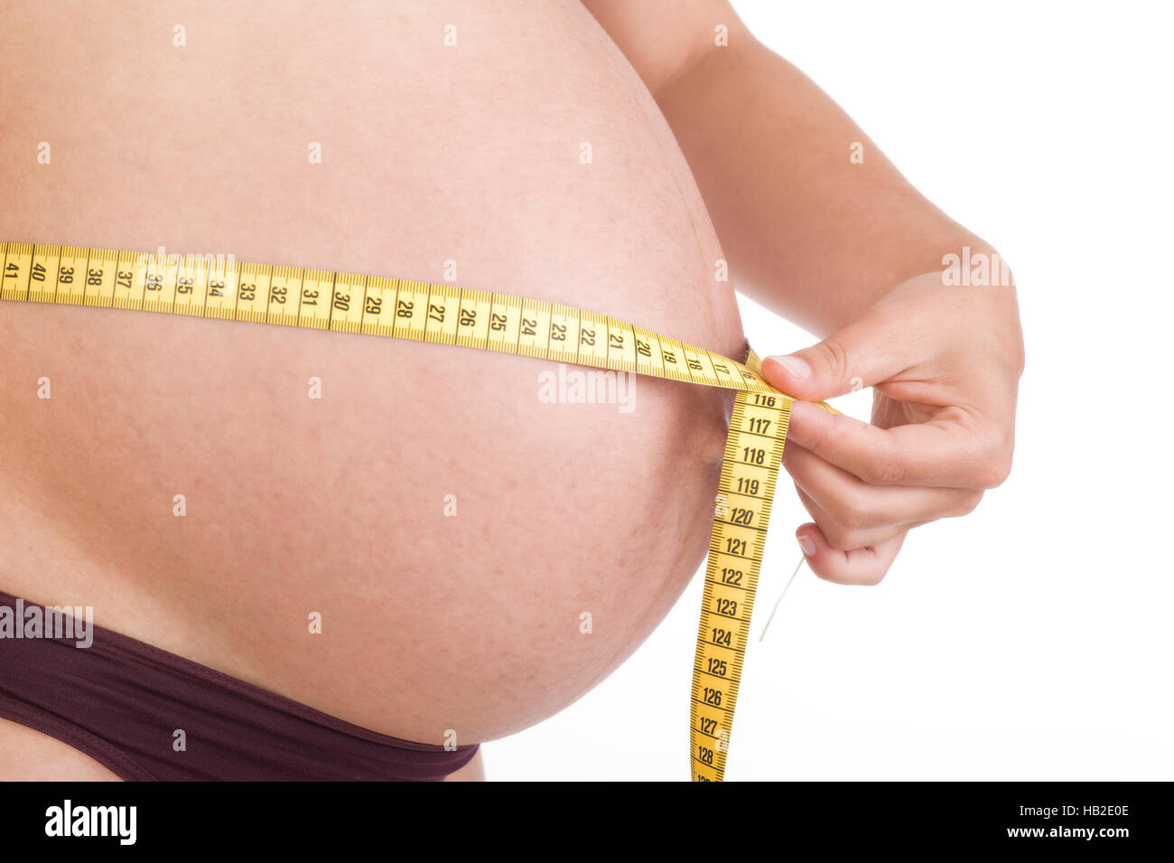 Donna incinta misurando la sua circonferenza addominale con un nastro di misurazione Foto Stock