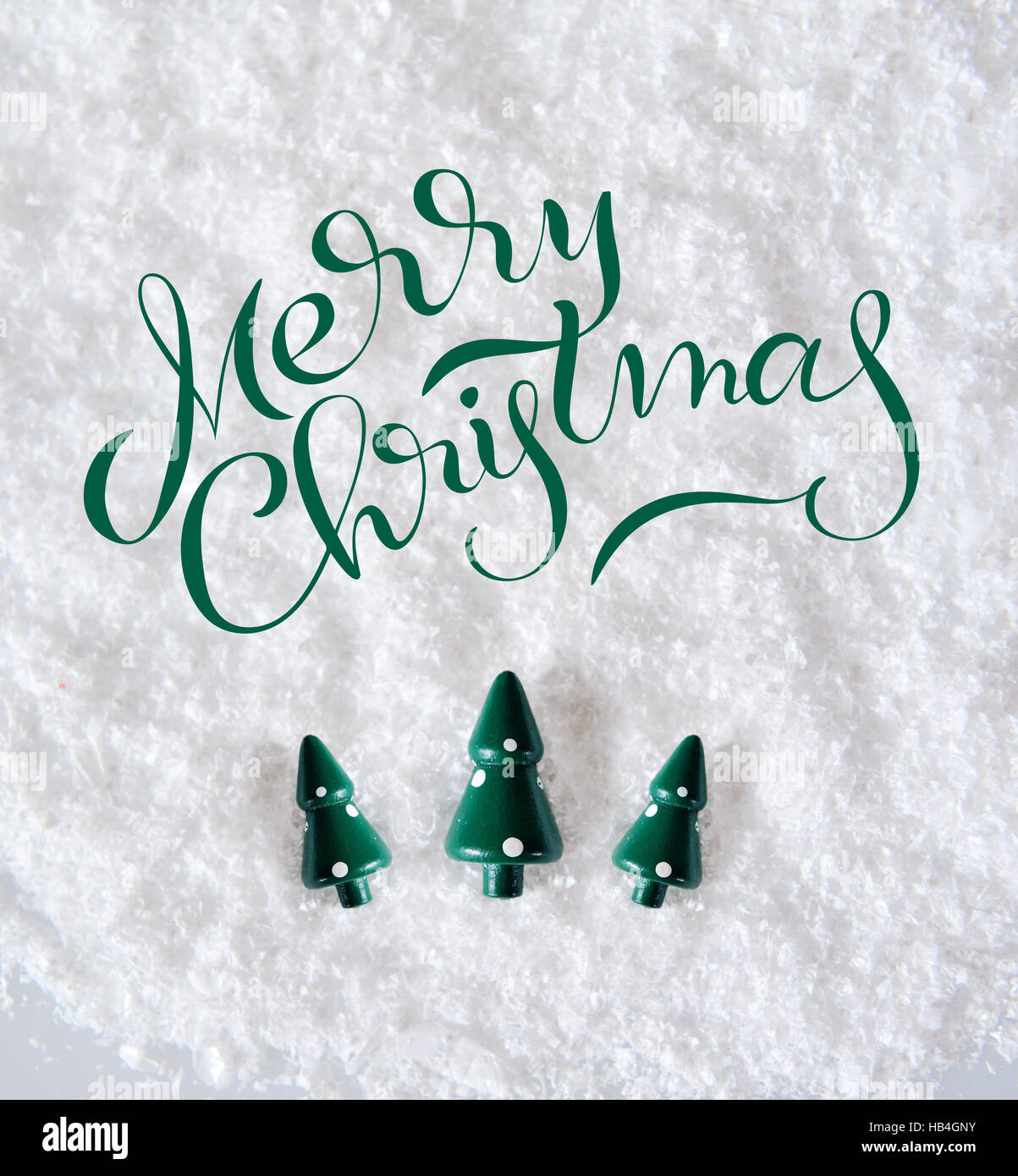 Tre alberi in miniatura sulla neve con testo Buon Natale. Lettering calligraphy Foto Stock