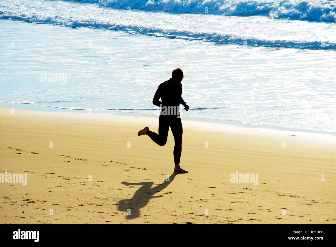Silhouette di un uomo che corre sulla spiaggia Foto Stock