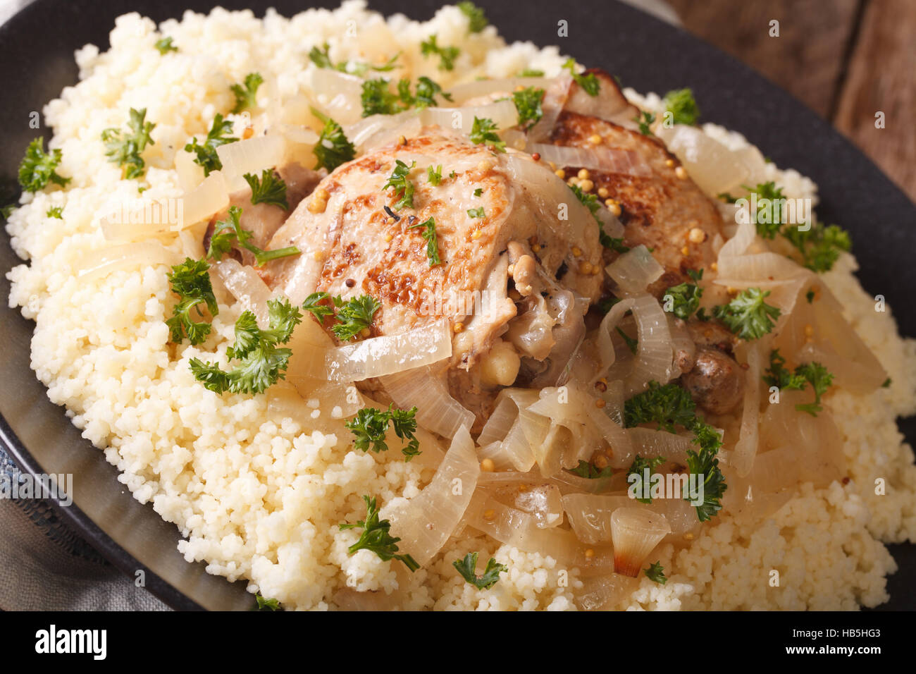 Tradizionale cibo africano: poulet Yassa con la cipolla e il cuscus macro sul tavolo orizzontale. Foto Stock