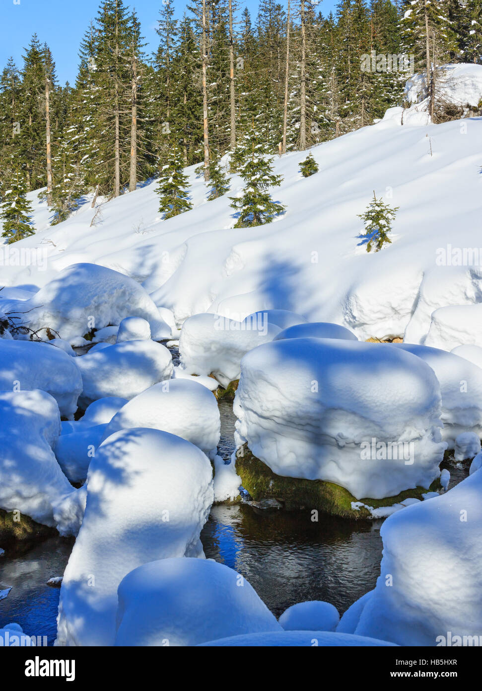Piccolo ruscello di montagna con cumuli di neve. Foto Stock