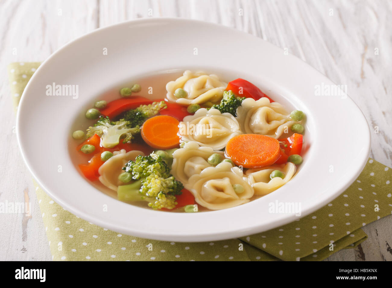 Tortellini italiano minestra con broccoli, piselli, carote e pepe close-up sulla piastra della tavola orizzontale. Foto Stock