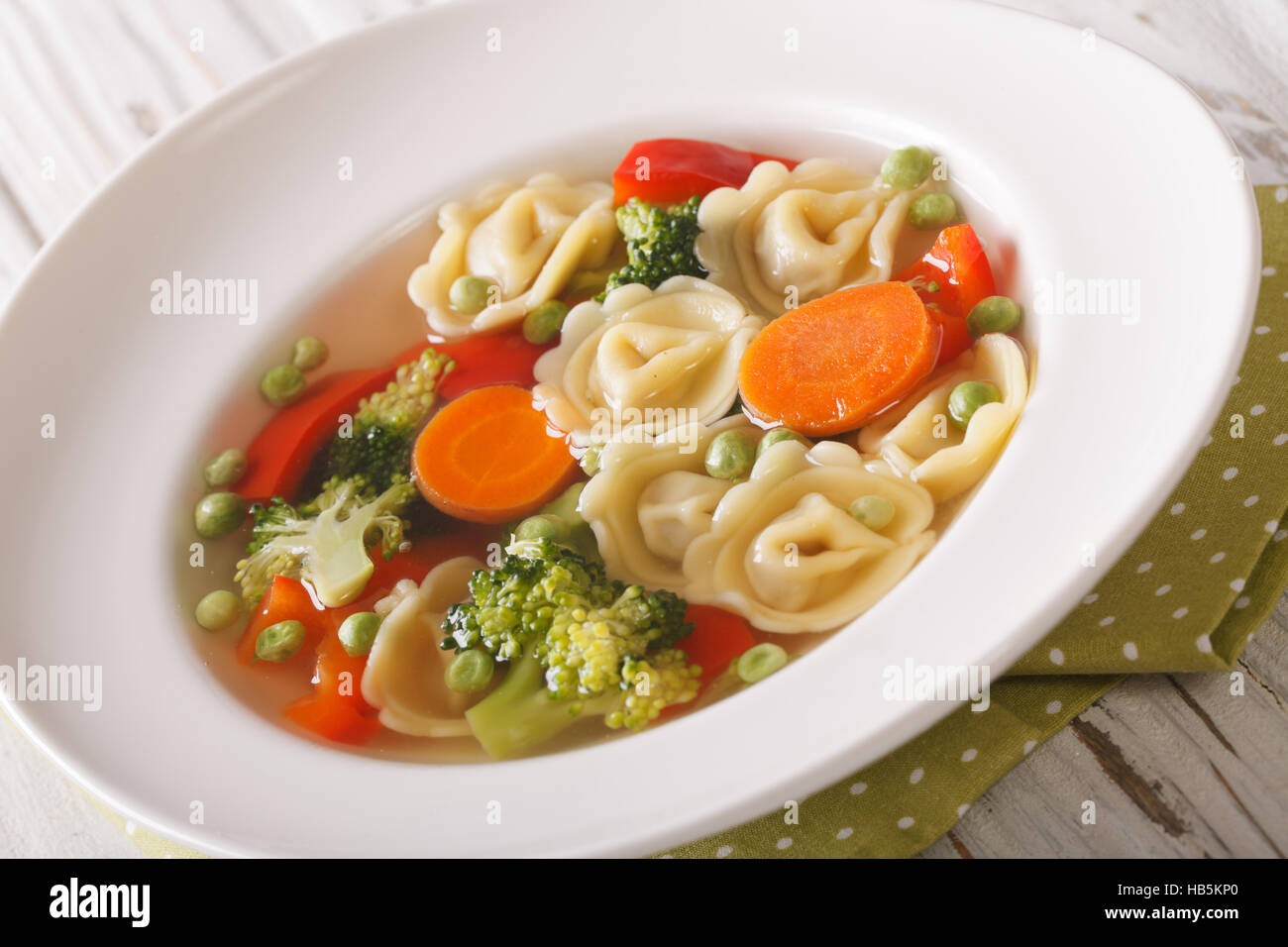 Tortellini calda zuppa di broccoli, piselli, carote e pepe close-up sulla piastra della tavola. Posizione orizzontale Foto Stock