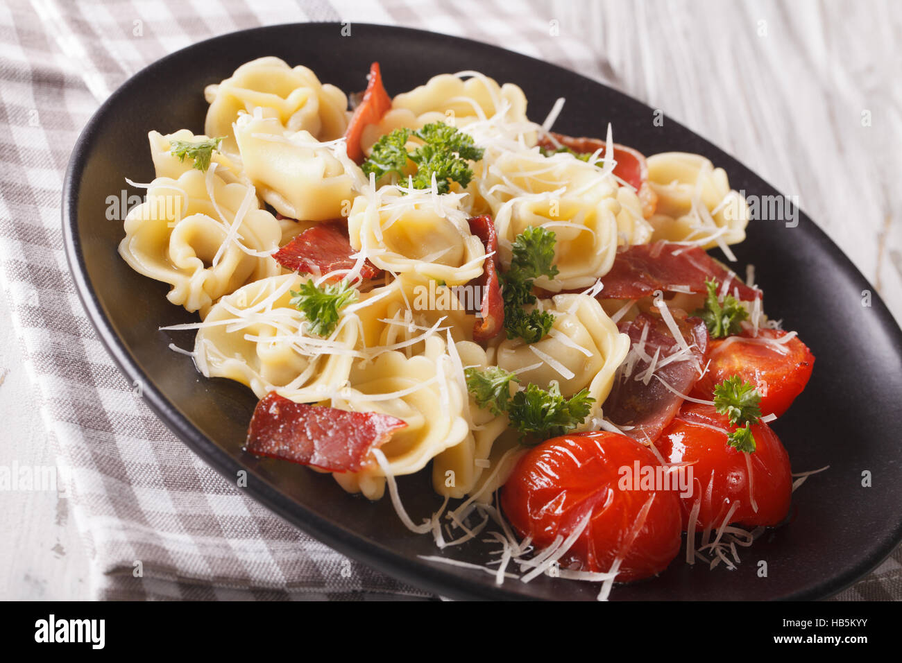 Italian tortellini con prosciutto, pomodori e parmigiano close-up su una piastra. Posizione orizzontale Foto Stock