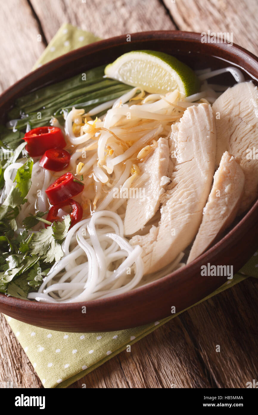 Zuppa vietnamita pho ga con pollo e riso tagliatelle, i germogli di soia e peperoncino in una ciotola di close-up verticale. Foto Stock