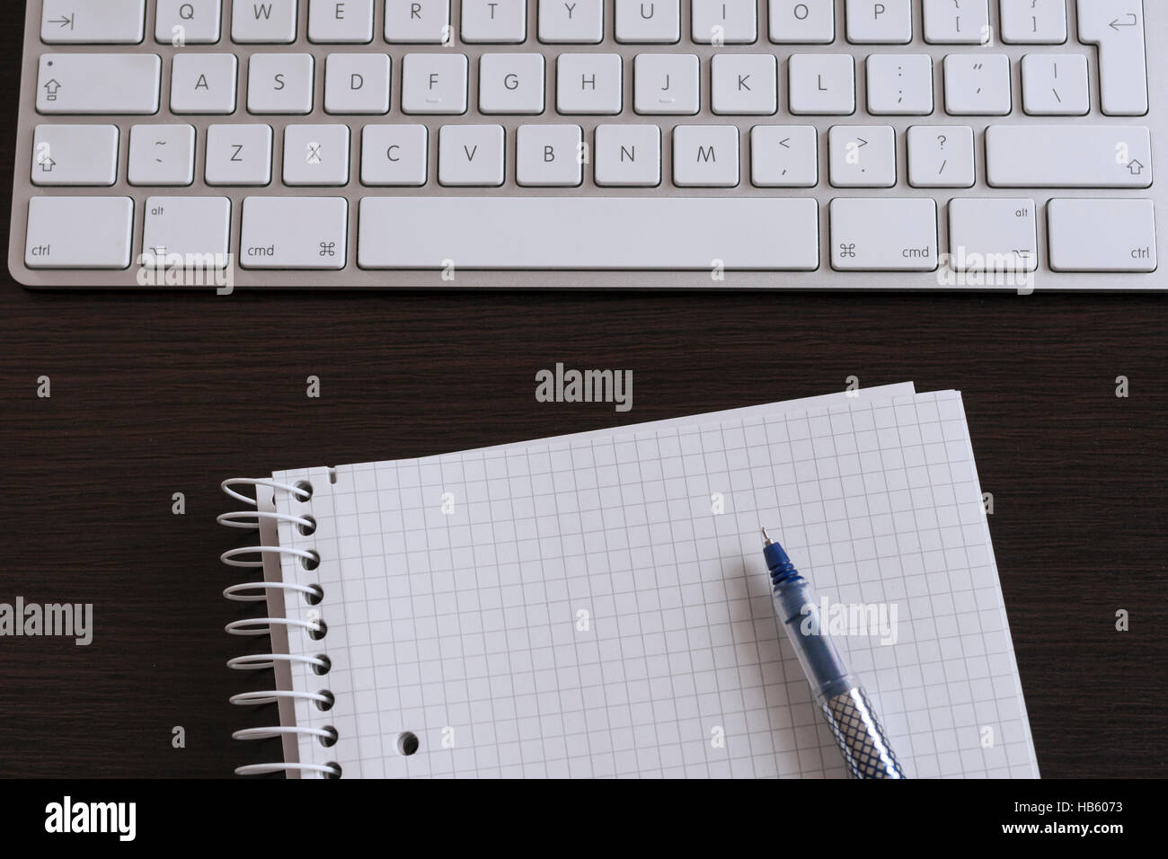 Notebook e penna sulla scrivania accanto alla tastiera del computer Foto Stock