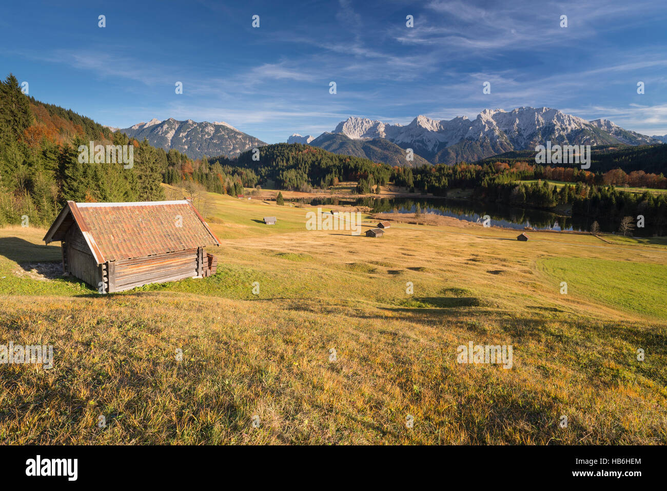Pagliaio sopra il lago di Gerold e sulle montagne del Karwendel Circondato da colorati humpy prati e bosco in autunno nel pomeriggio la luce solare, Baviera, Germania Foto Stock