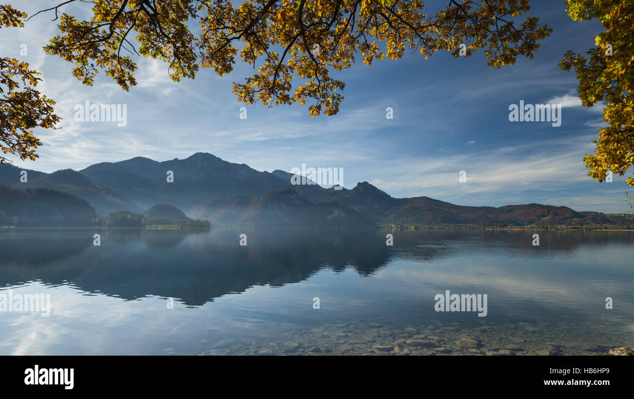 Alberi colorati con foglie di autunno al di sopra del lago Kochelsee riflettendo il panorama del Monte Herzogstand nelle Alpi Bavaresi, Baviera, Germania Foto Stock