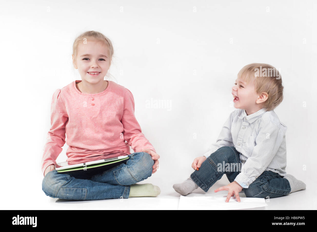 Ragazza utilizza tablet e ragazzo giocando con Chalk Foto Stock