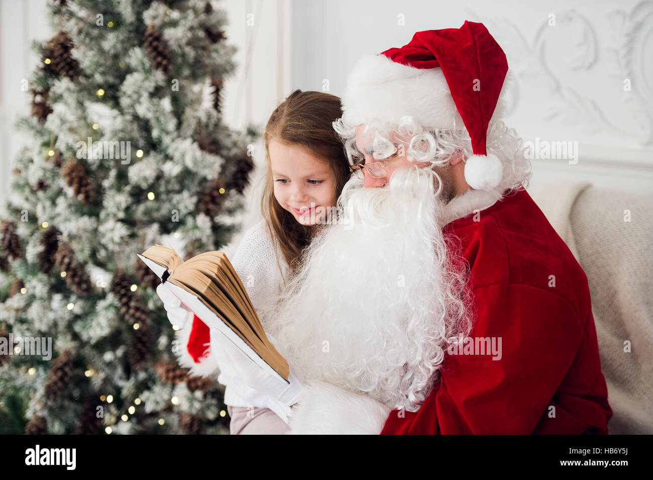 Bambino felice ragazza abbracciando Santa la lettura del libro e risate Foto Stock