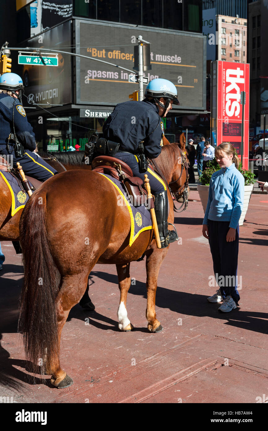 Una femmina di NYPD officer in sella ad un cavallo a parlare con una ragazza adolescente a Times Square di New York City, Stati Uniti d'America Foto Stock