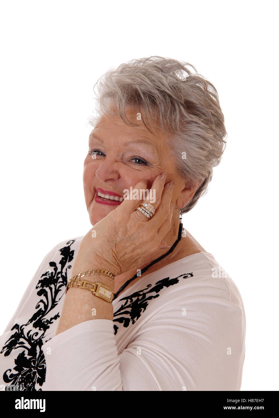 Sorridente donna senior tenendo la mano sul viso. Foto Stock