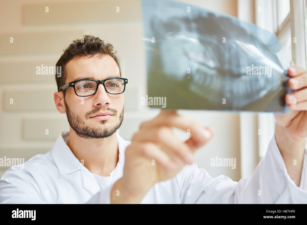 Dentista guardando immagine a raggi x con competenza Foto Stock