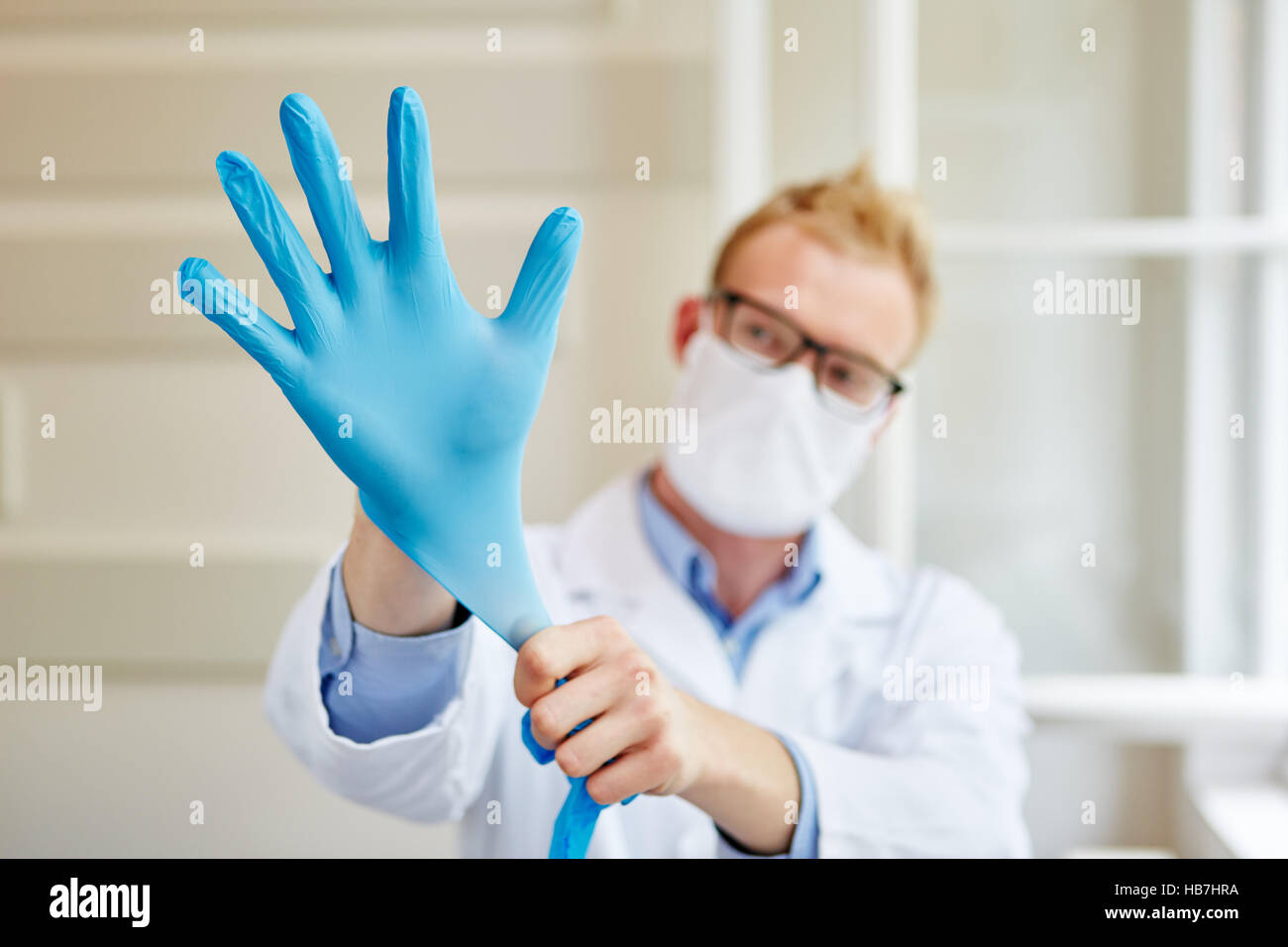 Medico di mettere guanti in quanto la protezione del lavoro Foto Stock