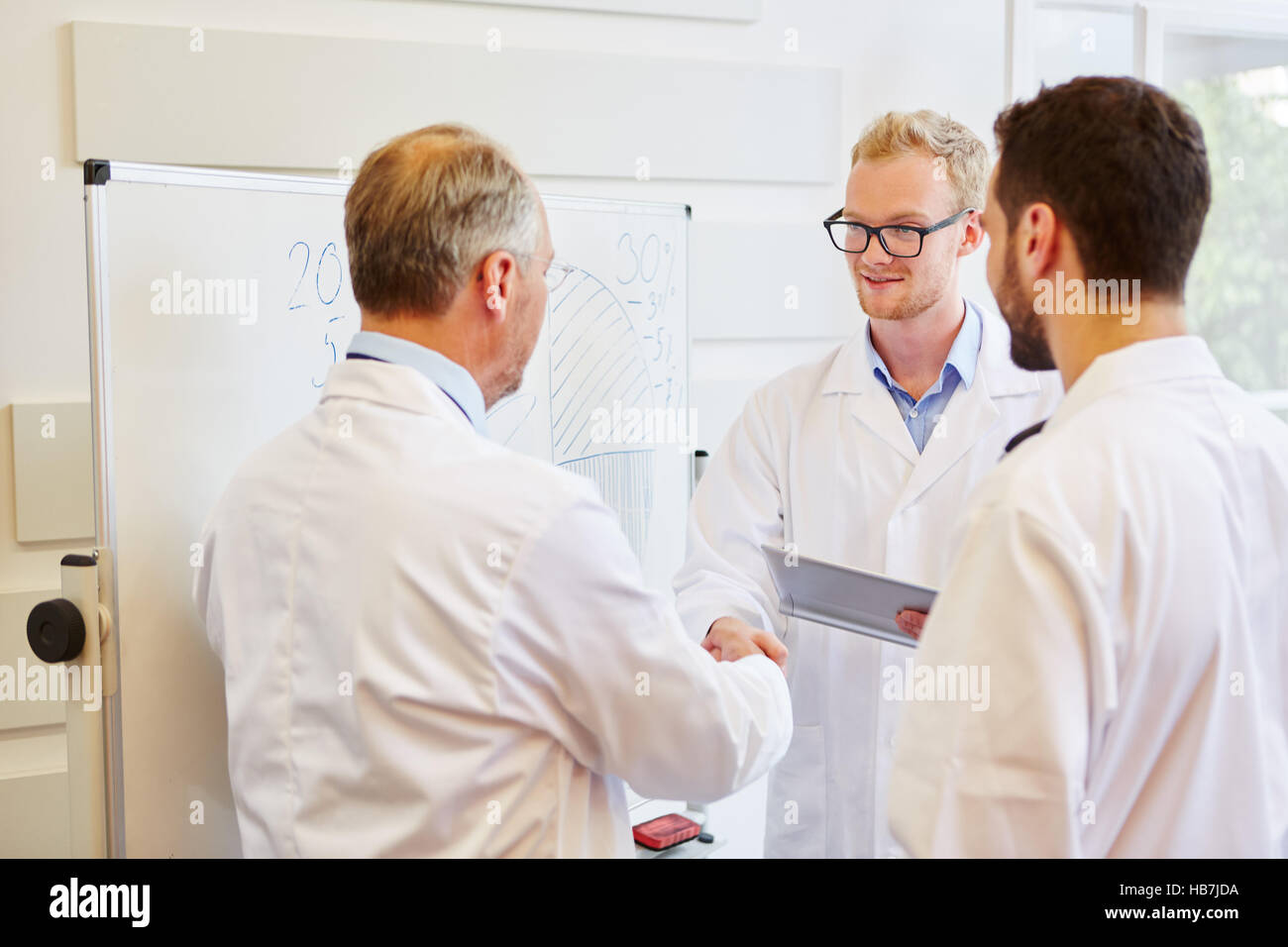 Senior medico si congratula con handshake per il successo del lavoro di squadra Foto Stock