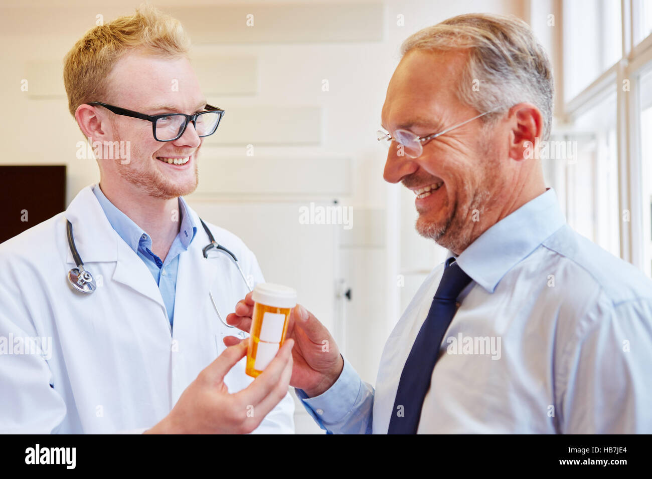 Il medico che prescrive un farmaco al paziente e dà a lui Foto Stock