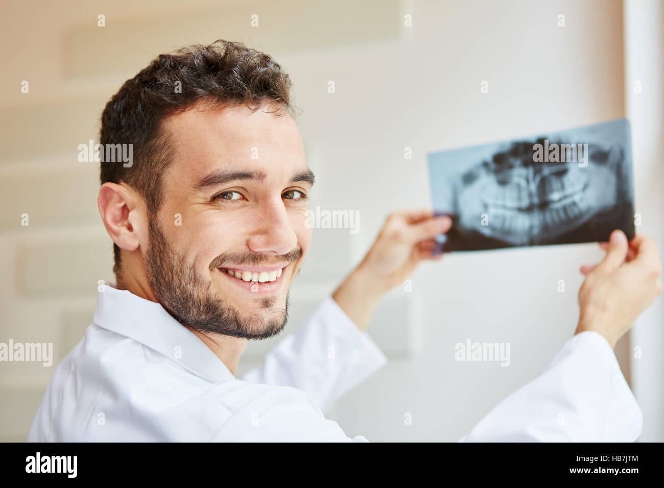 Dentista sorridente e tenendo premuto x-ray con gioia Foto Stock