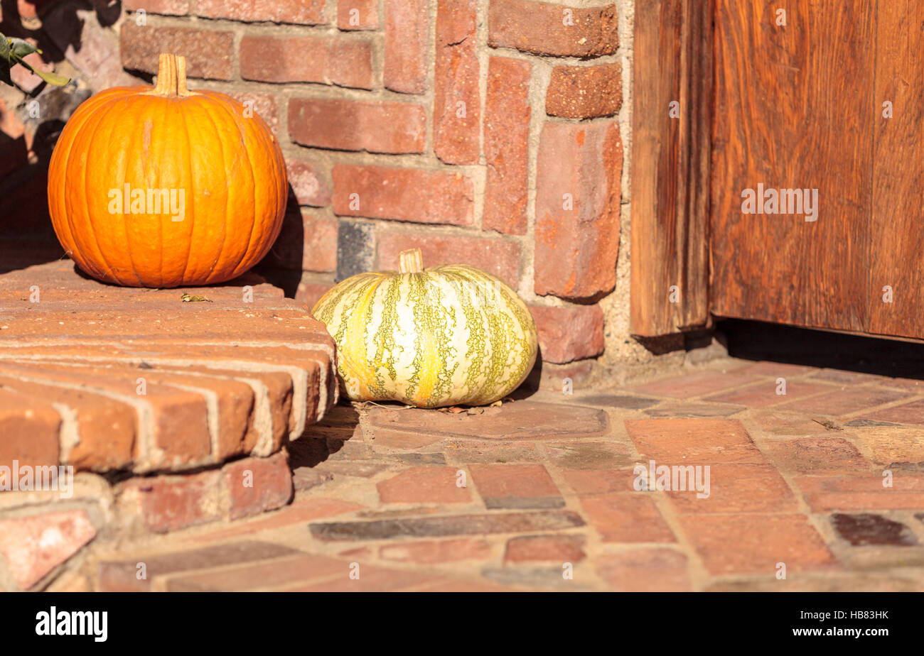 Un arancione zucca e una verde e zucca in bianco sulla parte anteriore fase di una casa in autunno. Foto Stock
