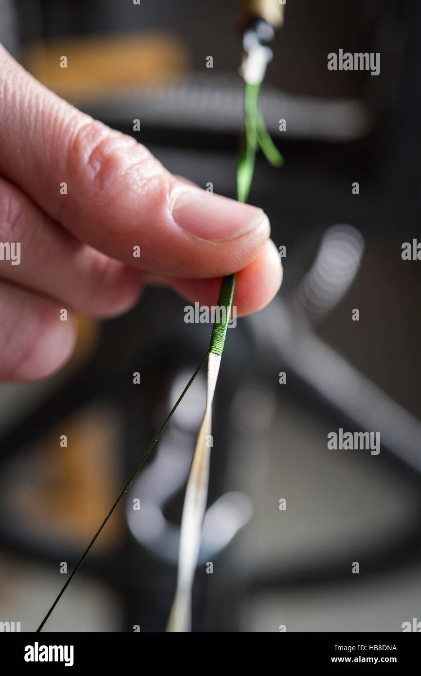 Passementerie maker, mano filo di guida sul cavo di alimentazione ruota di ritorcitura, filo di seta di essere attorcigliato intorno vellum, Monaco di Baviera Foto Stock