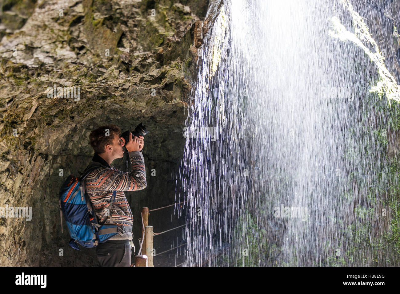 Giovane uomo prendendo fotografia dietro la cascata, Partnach Gorge, Alta Baviera, Baviera, Germania Foto Stock