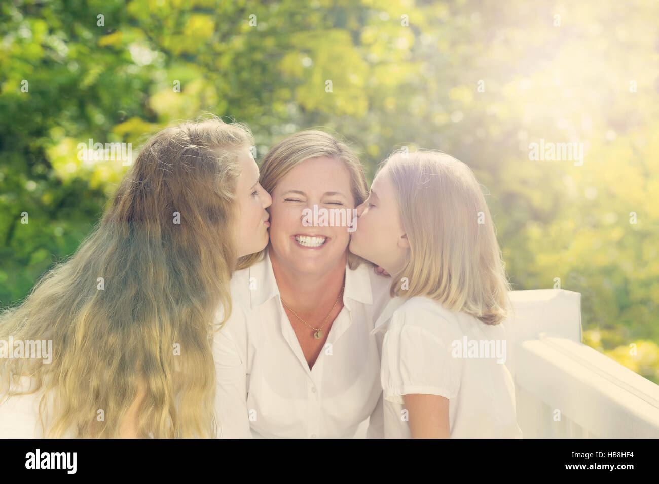 Madre riceve baci dalle sue figlie Foto Stock