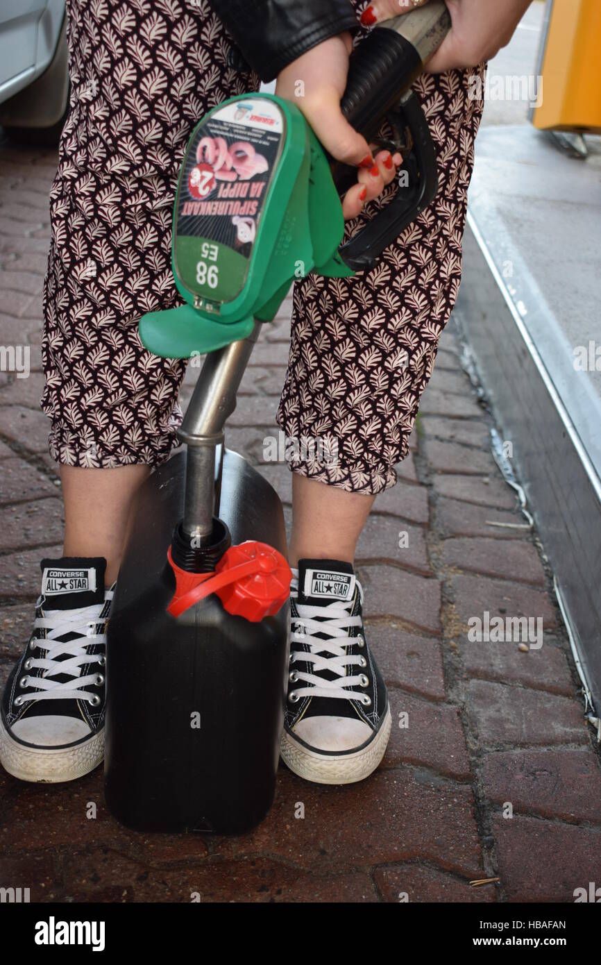 Giovane donna alimentando un possibile con tubi flessibili per benzina. Foto Stock